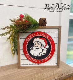 santa clause coming to town sign on wooden frame with pine branch and evergreen sprig