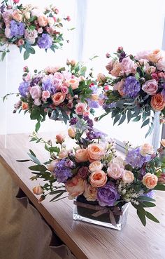 two vases filled with flowers on top of a wooden table