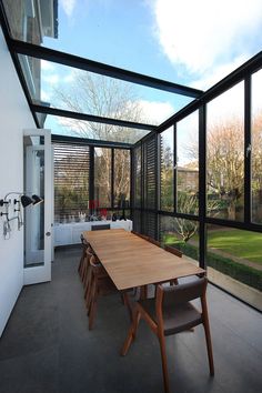 a dining room table and chairs in front of a large glass wall with sliding doors