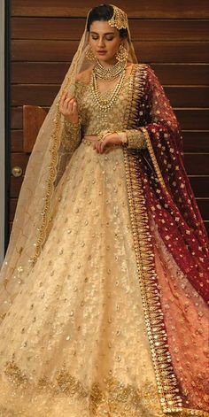 a woman in a white and red bridal gown standing next to a wooden wall