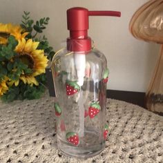 a glass bottle with strawberries on it sitting on a table