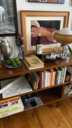 a shelf with books, figurines and other items on it in front of a painting