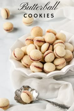 a white bowl filled with cookies on top of a table next to a silver spoon