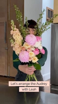 a woman holding a bouquet of flowers in front of her face and looking at the camera