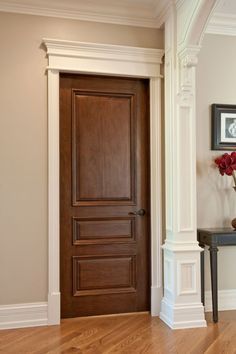 a wooden door is in the middle of a room with white trim and wood floors