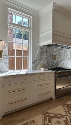 a kitchen with marble counter tops and white cabinets, along with an area rug on the floor