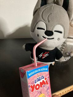 a stuffed animal with a drink in it's mouth sitting next to a box of yogurt