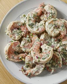 a white plate topped with shrimp covered in sauce and garnished with fresh herbs