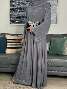 Elevate Your Elegance with Our Occasion Abaya Set Indulge in luxury with our Occasion Abaya Set, available in sophisticated Grey hues. This four-piece ensemble is a masterpiece of design, featuring convenient pop-up buttons for effortless wear. Exquisite Details, Unmatched Comfort Adorned with intricate gemstone embellishments, the outer jacket abaya is gracefully separated from the inner closed abaya. The inner layer is crafted from 100% Premium Nida fabric, ensuring lightweight and sumptuously Party Abaya Designs, Wedding Abaya Design, Abaya Designs Latest Dubai, Luxury Abaya Dubai, Elegant Abaya Designs, New Wedding Dress Indian, Party Wear Abaya, Jacket Abaya, Abaya Fashion Modern