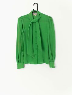 Vintage 70s Gina Fratini blouse with a tie front collar, long sleeves with button. In bright green. Would look lovely with some flared trousers or mini skirt.  Our recommended size: XXS  Label says: 10 Condition: Very good, tiny hole/pull in front (see last images, not colour accurate) Material: 100% wool Measurements in inches: Pit to pit: 15 Shoulders: 13.5 Front length: 24.5 Back length: 24 Sleeve length: 25 We've provided garment measurements and we recommend that you compare our measurement Spring Tie-neck Top With Button Closure, Spring Tie Neck Top With Button Closure, Spring Tie Neck Tops With Button Closure, Green Long Sleeve Blouse With Button Closure, Fitted Tie Neck Blouse With Button Closure, Elegant Long Sleeve Green Blouse, Casual Fitted Tie Neck Blouse, Green Button Closure Blouse For Office, Casual Fitted Blouse With Tie Neck