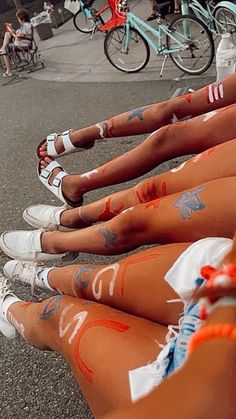 several women with painted legs sitting on the ground