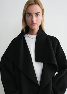 Signature coat crafted from TOTEME's soft doublé fabric – a blend of responsibly sourced wool and cashmere created by hand-stitching two fine layers together to achieve a double-faced finish with clean seams. It has an oversized silhouette with easy-to-style shawl lapels, dropped shoulders, and an open front which makes it perfect for layering, then is complete with inseam pockets and side slits. Coordinate it with the Long doublé scarf in the same color. Oversized Wool Outerwear With Shawl Collar, Classic Black Cashmere Wool Coat, Fall Cashmere Outerwear With Shawl Collar, Black Cashmere Wool Coat For Winter, Winter Black Cashmere Wool Coat, Cashmere Outerwear With Shawl Collar For Winter, Black Cashmere Outerwear For Work, Cashmere Shawl Collar Outerwear For Winter, Modern Long Sleeve Cashmere Outerwear