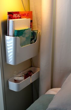 a bed room with a neatly made bed next to a wall mounted shelf filled with books and magazines