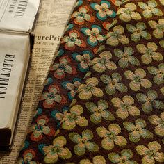 a close up of a tie on top of an old newspaper with a book in the background