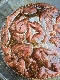 a pan filled with meat and seasoning on top of a stove