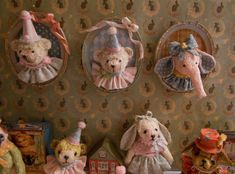 there are four stuffed animals hanging on the wall in front of two frames with teddy bears wearing hats and dresses