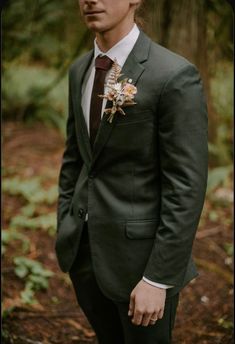 a man wearing a suit and tie standing in the woods