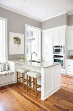 a kitchen with white cabinets and wooden floors