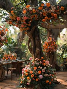 an arrangement of flowers is hanging from a tree in the middle of a room filled with tables and chairs