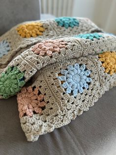 two crocheted granny afghans sitting on top of a couch next to each other