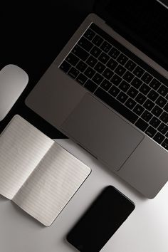 an open laptop computer sitting on top of a desk next to a mouse and cell phone