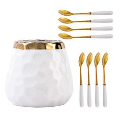 a set of four gold and white spoons next to a cup with five forks