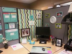 an office cubicle with a computer, phone and pictures on the wall behind it