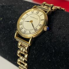 Vintage Tiffany & Co 14k Yellow Gold Quartz 20.5 Mm Watch. The Face Is An Off White Color And Has Black Roman Numerals, "Tiffany & Co." And "Swiss" Writing. There Is A Blue Shappire In The Crown Dial. There Is A Small Crack On The Face And Only Noticable When Upclose. Small Scuffs On The Gold From Wear. This Is Estimated To Be 1960-80’s And Is Amazing Condition For Its Age. It Works Great And A New Battery Was Installed 01/18/2024. I Would Suggest Measuring Your (Or Your Ladies) Wrist As The Band Is Short. It Is Right At 6 Inches Long To The Lock Position. There Is A Double Lock Latch On Both Sides Of The Clasp. Per A Verbal Appraisal Watch Is Estimated Price Range Of 4-5k. Please See All Classic Yellow Gold Watch For Gift, Timeless Yellow Gold Jewelry And Watches For Formal Occasions, Timeless 14k Gold Watch With Polished Finish, Classic Yellow Gold Jewelry For Formal Occasions, Timeless Yellow Gold Jewelry And Watches, Polished Finish, Timeless Gold Jewelry And Watches With Round Shape, Classic 14k Yellow Gold Watch, Classic Formal Jewelry And Watches With 17 Jewels, Timeless Polished Yellow Gold Jewelry