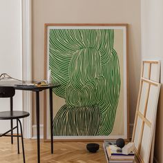 an art work is displayed in the corner of a room with two chairs and a table