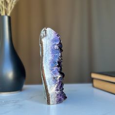 a purple and white rock sitting on top of a table next to a black vase