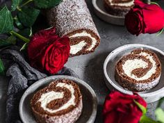 two plates with pastries on them next to roses