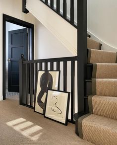 an entryway with stairs and pictures on the floor next to it in front of a black door