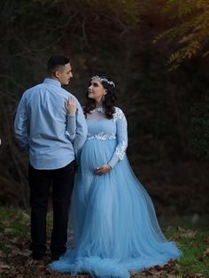 a pregnant woman in a blue dress standing next to a man