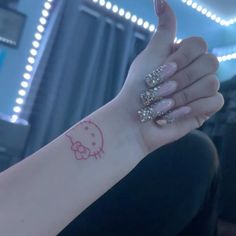 a woman's hand with a hello kitty tattoo on it, in front of a mirror