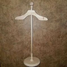 a white coat rack on top of a wooden table next to a wall with a brown background