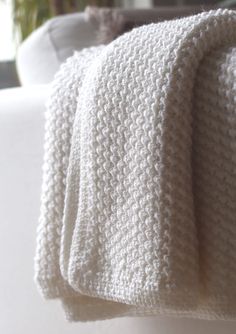 a white knitted blanket sitting on top of a bed