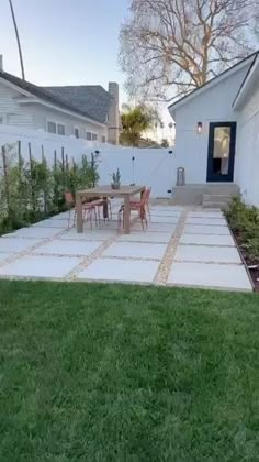 an outdoor patio with table and chairs next to a white fenced in backyard area