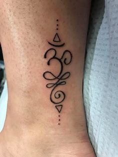 a woman's foot with a tattoo design on the side of her ankle and an omen symbol