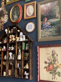 there are many framed pictures on the wall and some shelves with vases in them