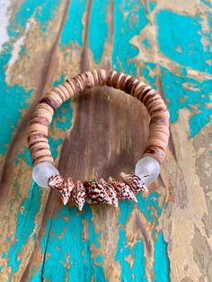 This beautiful natural tiger shell bracelet looks great alone, or stacked with our other beachy pieces! The coconut shell beads are accented with 7 tiny brown and white tiger shells, flanked on each end by light green sea glass beads. The perfect complement to your swimsuit and coverup while at the beach or by the pool, or with your everyday outfit to add a bit of coastal style. This bracelet is sized at 7 inches. If you would like a larger or smaller bracelet, please contact me. Due to the natu Bohemian Beaded Oyster Bracelets For Beach, Bohemian Oyster Beaded Bracelets For Beach, Spiritual Beach Stretch Bracelet, Shell Beaded Bracelets For Beach Season, Earthy Beaded Bracelets For Beach, Earthy Brown Beaded Bracelets For Beach, Bohemian Brown Bracelets For Vacation, Earthy Brown Bracelet For Beach, Earthy Brown Bracelets For Beach