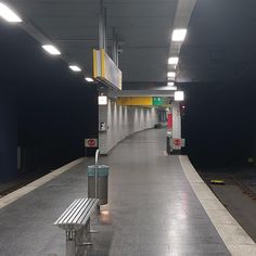 an empty subway station with benches and lights on the side walk in front of it