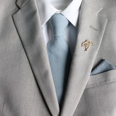 a man wearing a suit and tie with a tree pin on his lapel