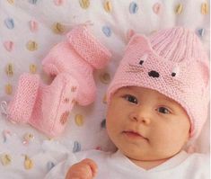 a baby wearing a knitted bear hat and mittens laying on top of a blanket