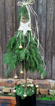 a small christmas tree with ornaments hanging from it's branches in front of a wooden fence