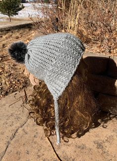 a knitted hat with a pom - pom sits on top of a woman's head