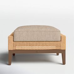 the foot stool is made out of wicker and has a cushion on one end