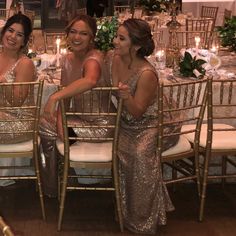 three women in sequin dresses sitting at a dinner table with candles on the tables