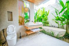 a bathroom with a sink, toilet and bathtub surrounded by greenery on the walls