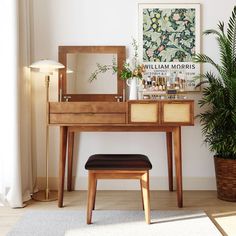 a wooden desk with a mirror, stool and potted plant in front of it