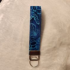 a blue flowered keychain with a metal ring on top of white fabric